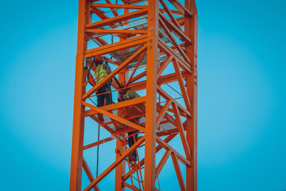 Arbeiter klettern Kran nach oben mit Sicherheitsausrüstung